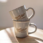 Two stacked metal mugs with 'Dear Madeline Florals' engraving on a wooden surface.